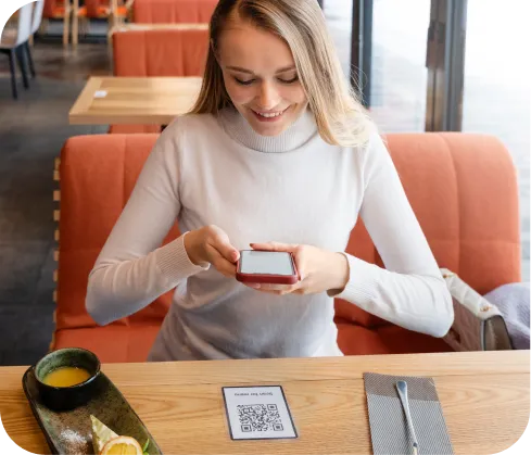 Mujer emprendedora sonriente usando celular para cobrar con Poket