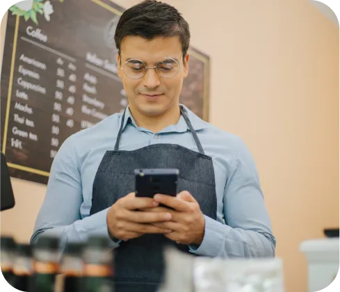 Hombre emprendedor sonriente usando celular para recibir pagos con Poke