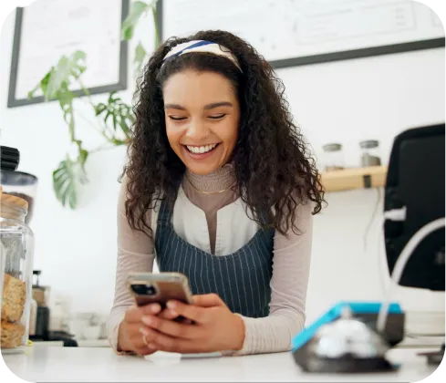 Mujer emprendedora sonriendo usando celular para cobrar con Poket