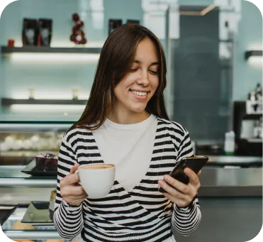 Mujer emprendedora en su cafetería usando celular para cobrar con Poket